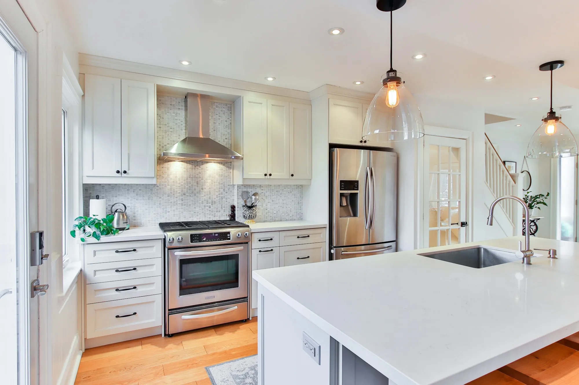 White kitchen with stainless range and a quartz island