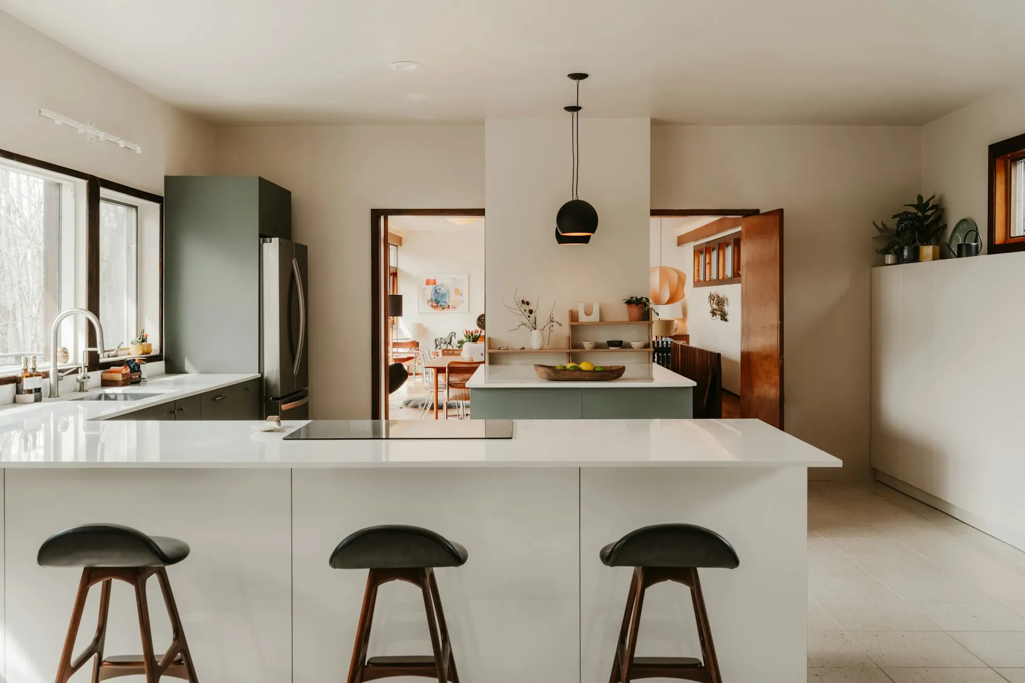 White kitchen island with bar stools and a view to the next room