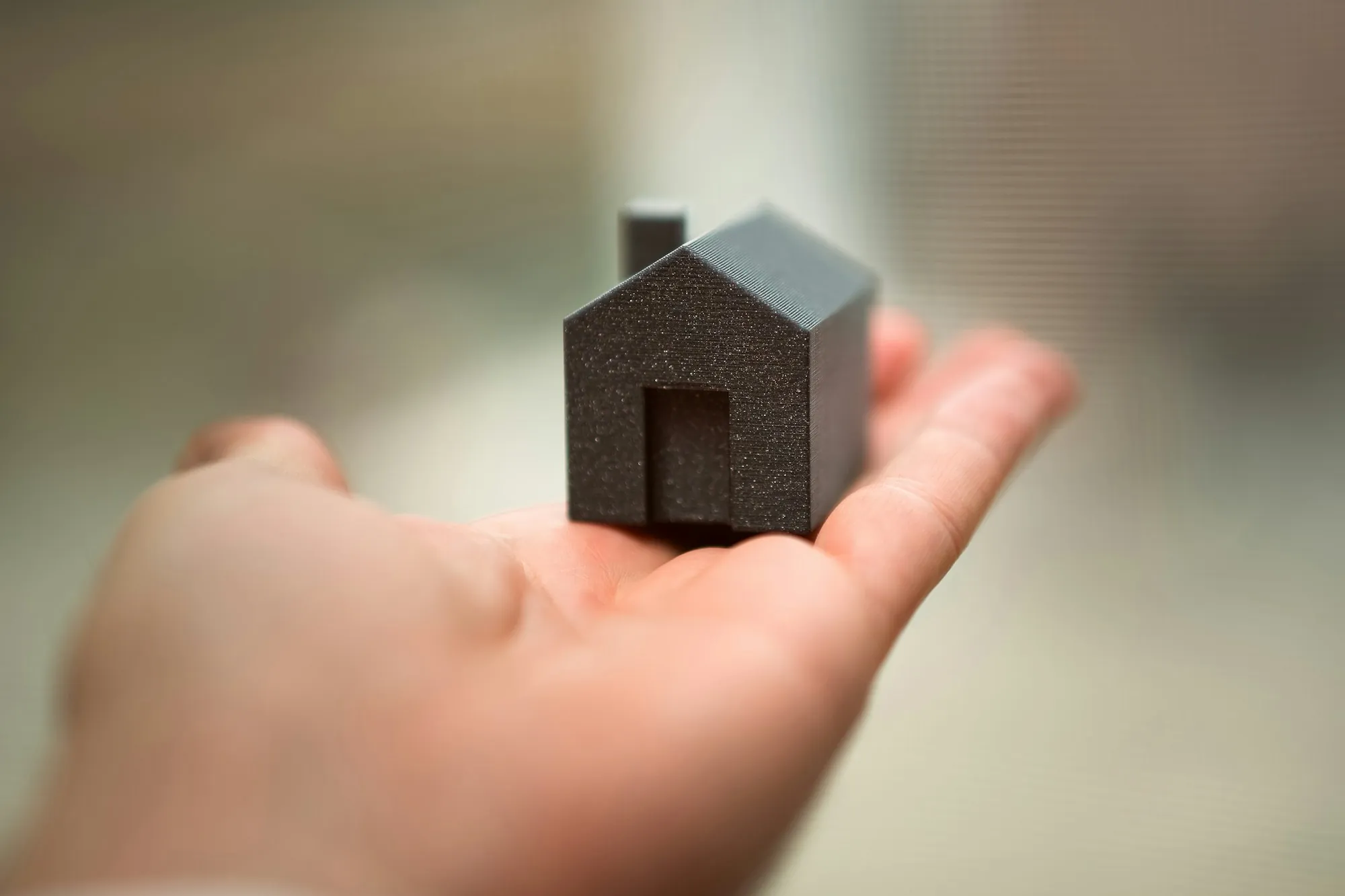 Open hand holding a small dark model house