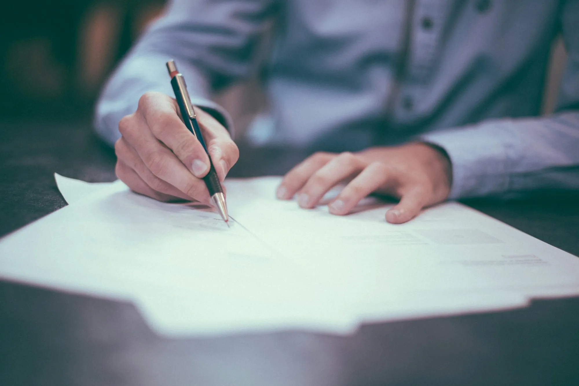 Hand signing a contract with a pen